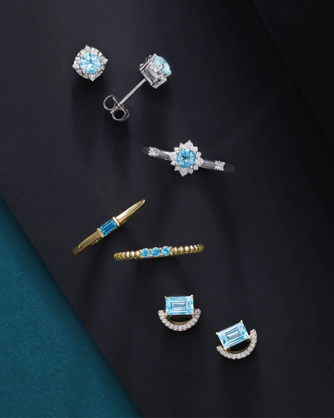 Blue gemstone rings and earrings arranged on dark fabric