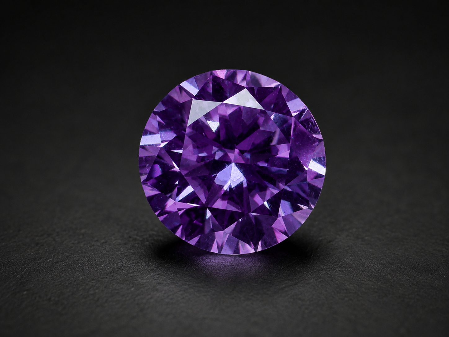 Purple cut moissanite shown upright against a dark surface